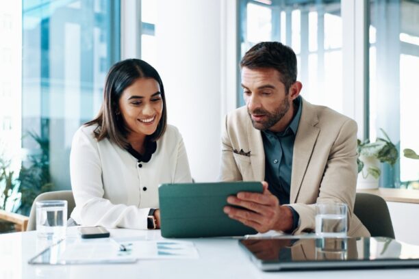 Two professionals reviewing data on tablet in modern office