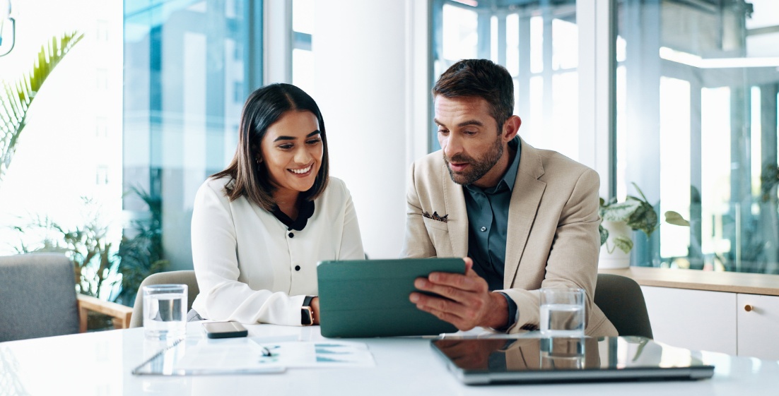 Two professionals reviewing data on tablet in modern office
