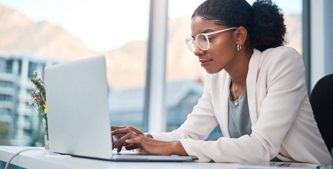 Professional woman typing on laptop in a bright office