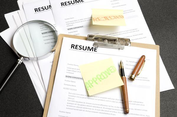 Pile of resumes with a magnifying glass