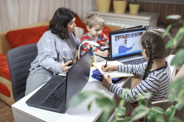 Woman working from home while her kids learn at her desk
