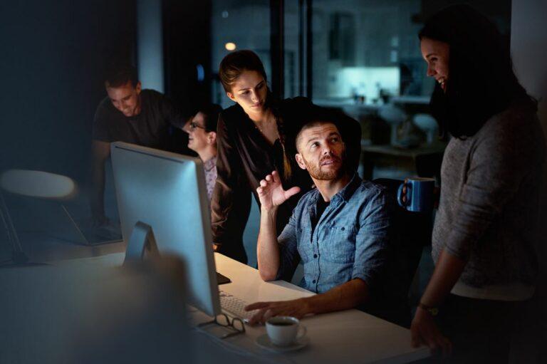 Shot of a group of colleagues using a computer together during a late night at work