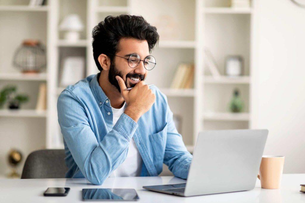 young man smiling and working on his laptop