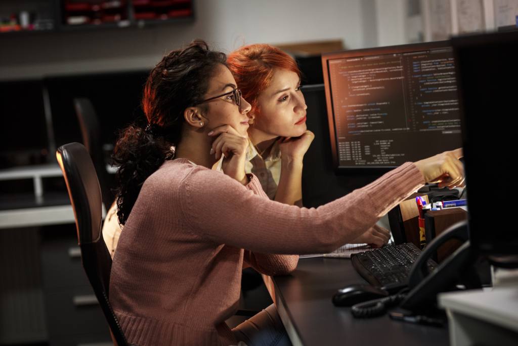 Two female programmers working on new project.They working late at night at the office.