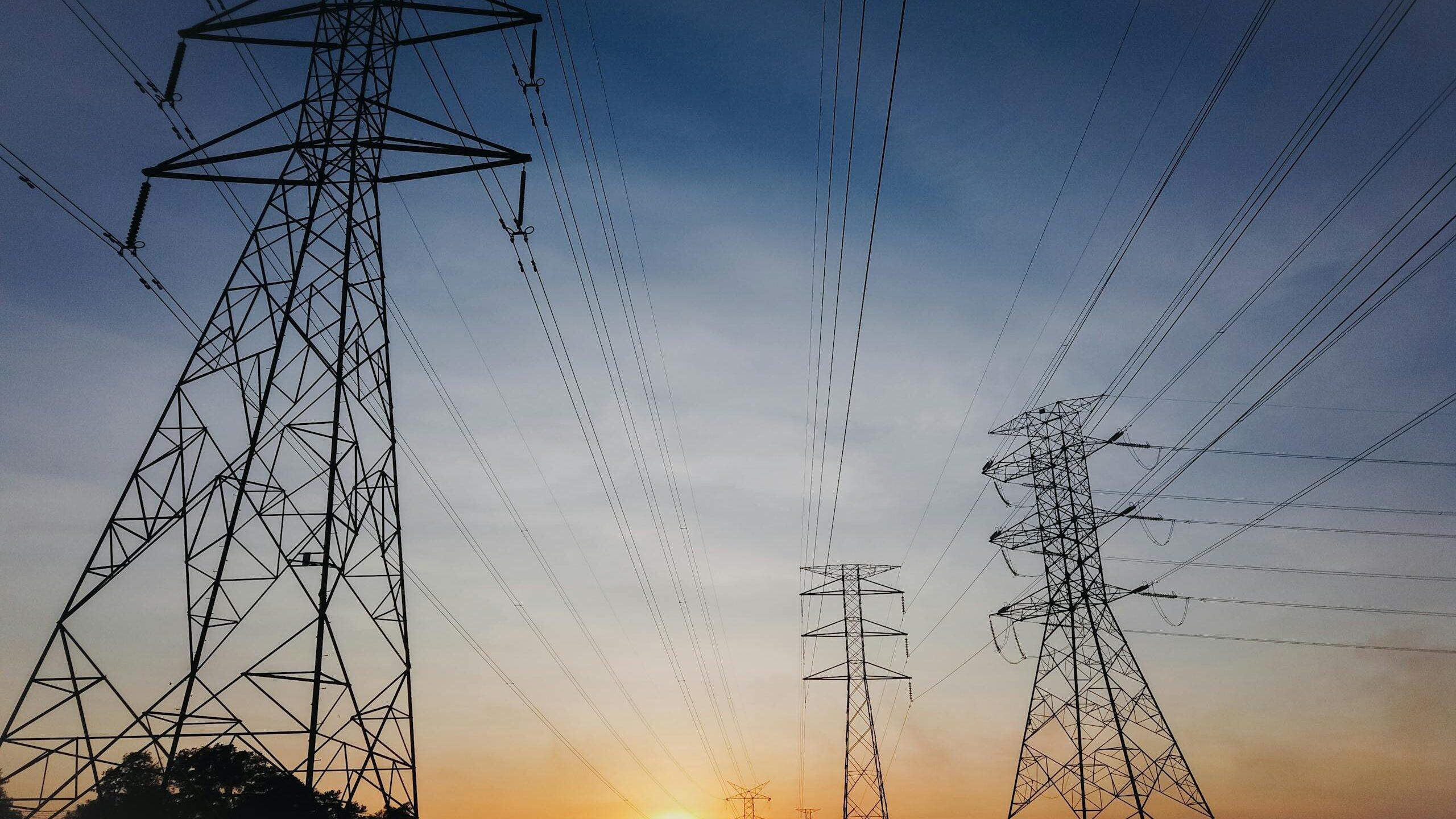 Scenery of contemporary electric power transmission lines located against picturesque sunset sky in evening countryside