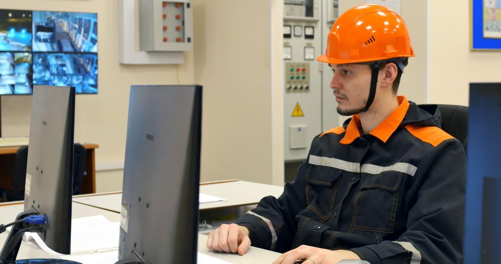 IT technician wearing an orange helmet in an office working on a computer