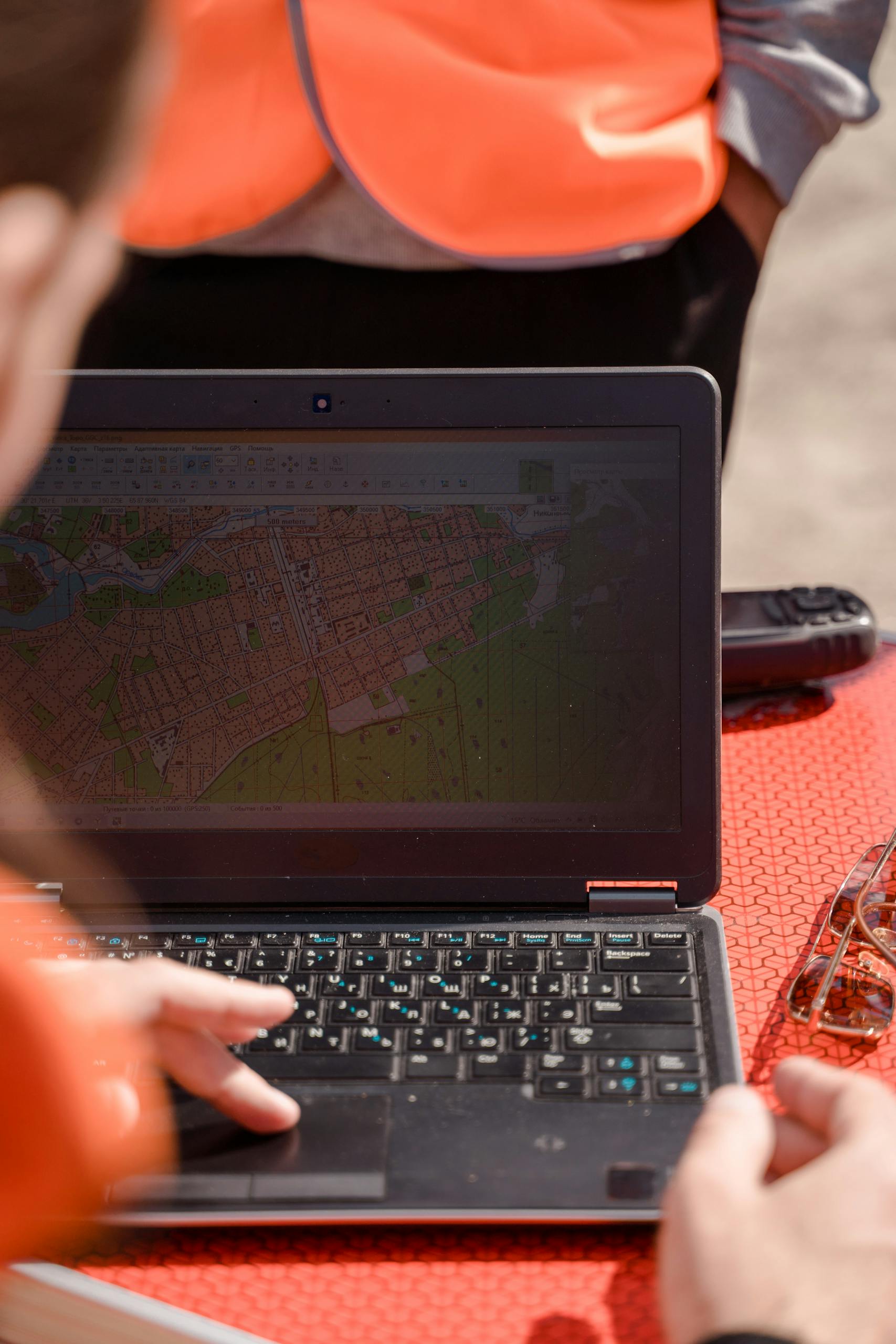 A field surveyor uses a laptop for mapping and navigation outdoors, ensuring accuracy.