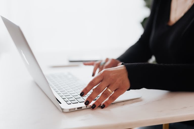 Crop unrecognizable female entrepreneur in casual clothes using touchpad on laptop while working at table in contemporary office