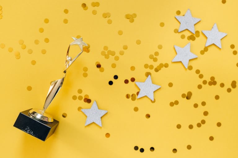 Shiny golden trophy and stars on a vibrant yellow background, symbolizing success and victory.