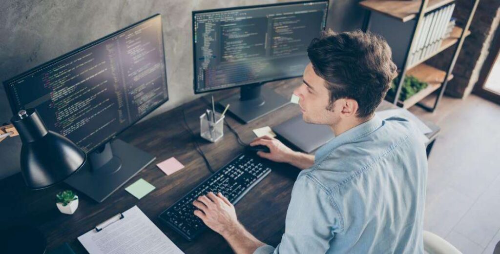 young male developer writing code at his desk