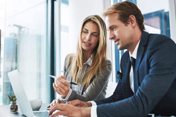 a male and female strategist working on a plan and typing it out on a laptop