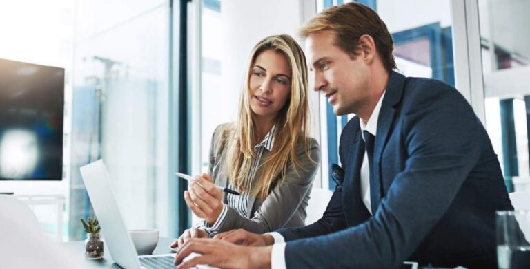 a male and female strategist working on a plan and typing it out on a laptop