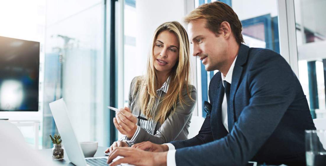 a male and female strategist working on a plan and typing it out on a laptop