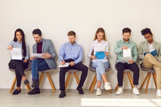 a row of job applicants sitting in a row and filling out a form