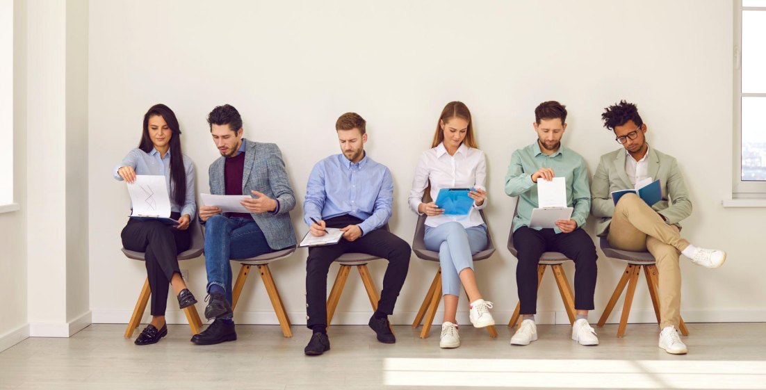 a row of job applicants sitting in a row and filling out a form