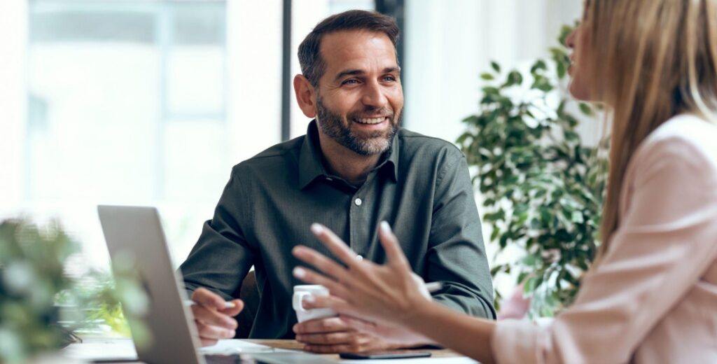 Colleagues having a friendly discussion at an office desk with laptop nearby