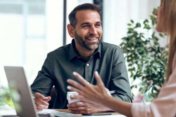 Colleagues having a friendly discussion at an office desk with laptop nearby