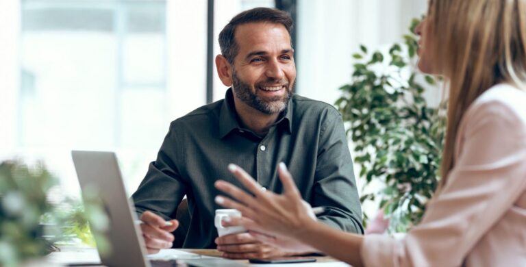 Colleagues having a friendly discussion at an office desk with laptop nearby