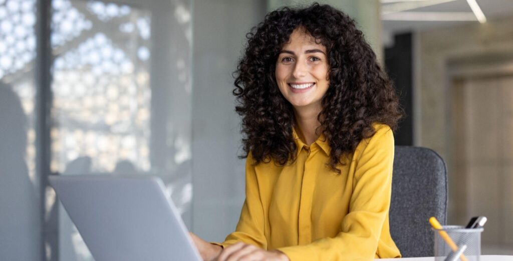 Curly-haired professional woman typing on a laptop