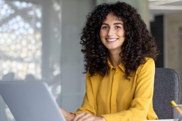 Curly-haired professional woman typing on a laptop