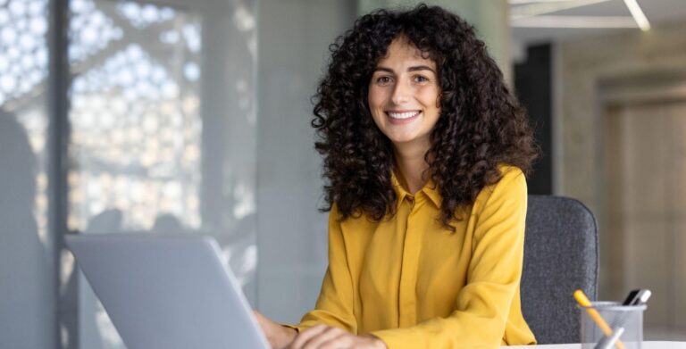 Curly-haired professional woman typing on a laptop