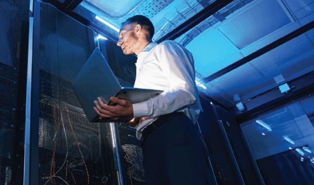 IT specialist inspecting server racks in a blue-lit data center