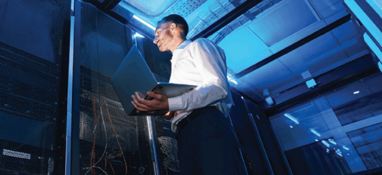IT specialist inspecting server racks in a blue-lit data center