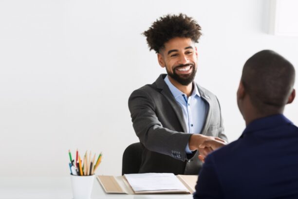 Professional handshake across a desk between colleagues