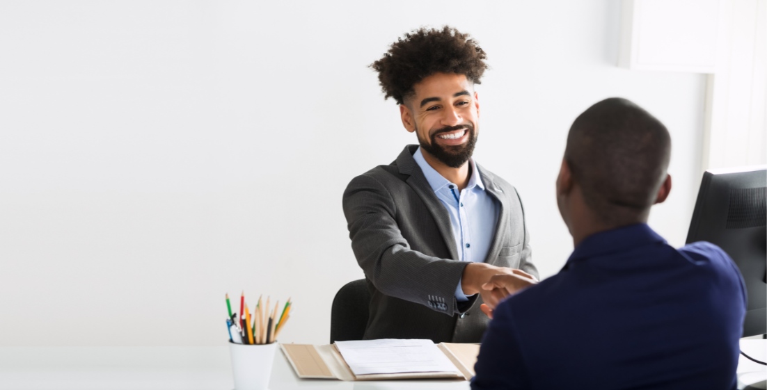 Professional handshake across a desk between colleagues