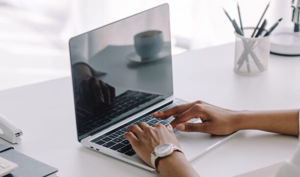 Woman typing on laptop at a minimalist white desk