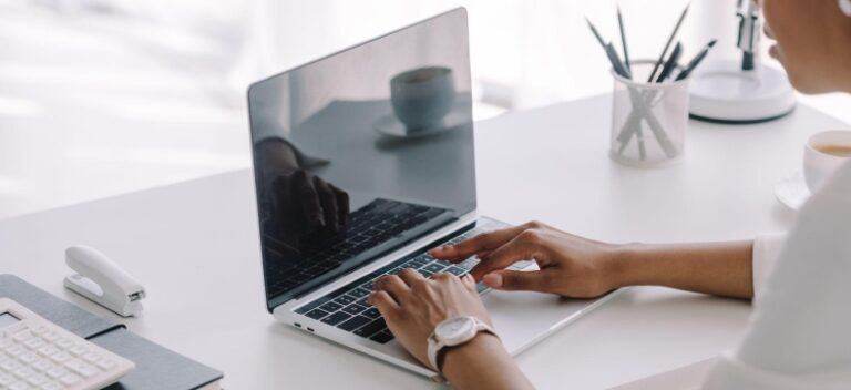 Woman typing on laptop at a minimalist white desk