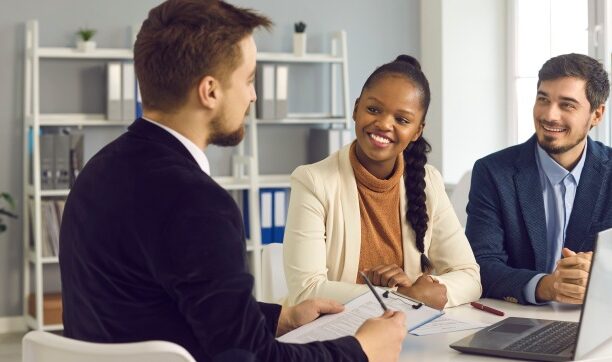 Diverse professionals in smiling discussion at office table with laptop and notes