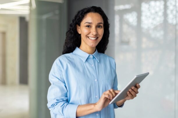 Smiling businesswoman holding tablet in modern office