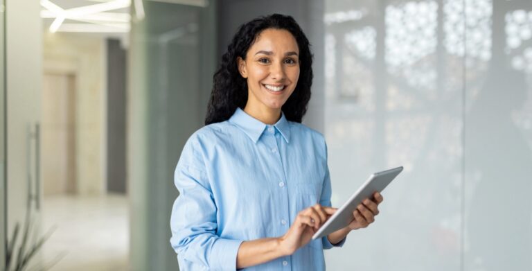 Smiling businesswoman holding tablet in modern office