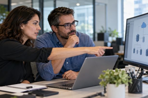 Two IT professionals review a cloud network architecture diagram on a monitor